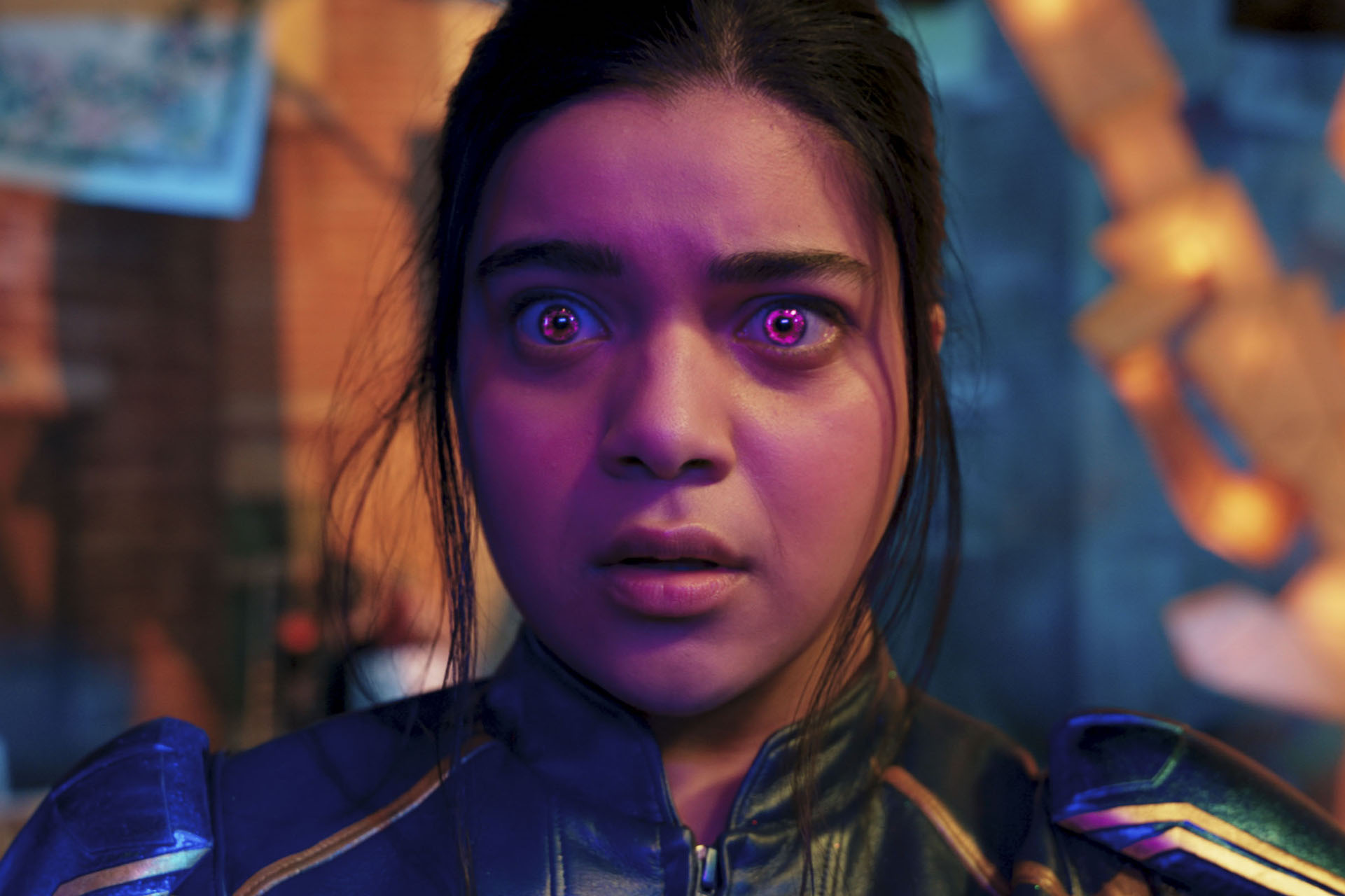 A teen girl in a superhero suit looking shocked, her eyes glowing reddish orange; still from "Ms. Marvel"